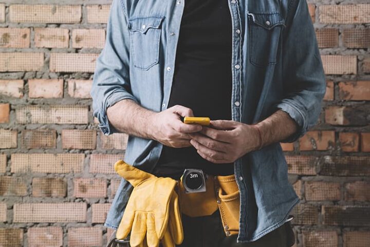Close up of a person holding a phone against a brick wall.
