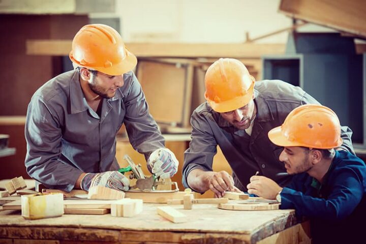 Three people in construction hats working with tools
