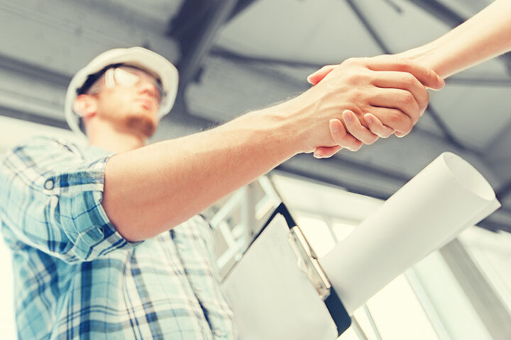 Onsite constuction worker handshake with blueprints.