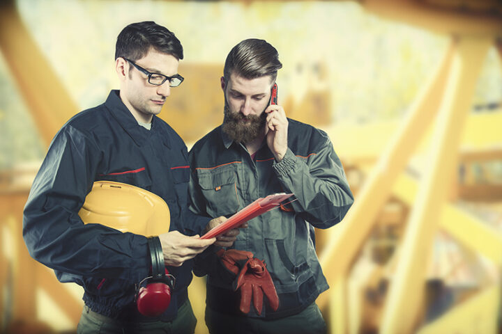 Two construction workers looking at clipboard