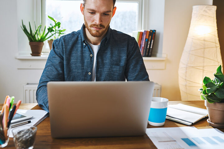 Man sitting at desk typing on laptop