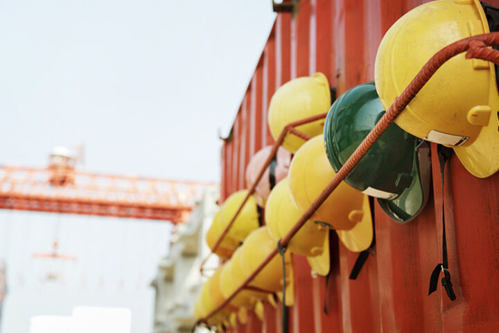 Construction hats hung outside on a red metal wall