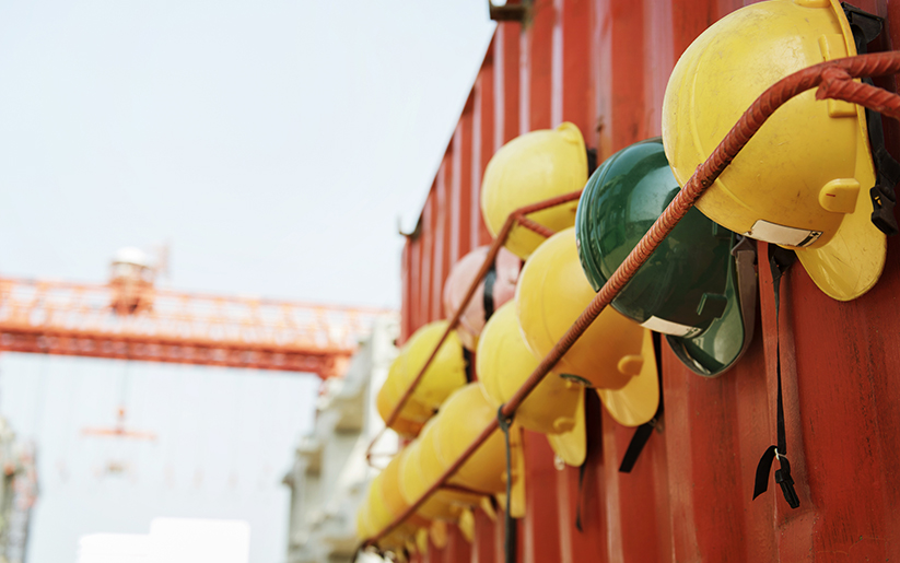 Construction hats hung outside on a red metal wall