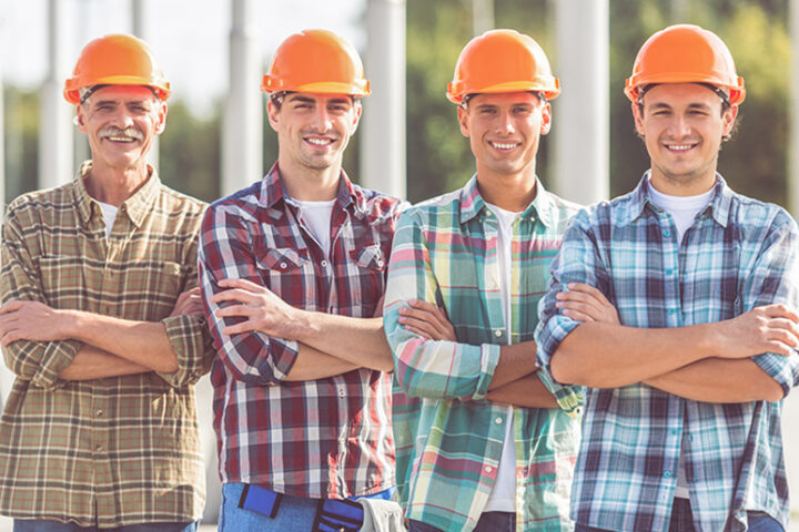Four construction workers lined up smiling with arms crossed