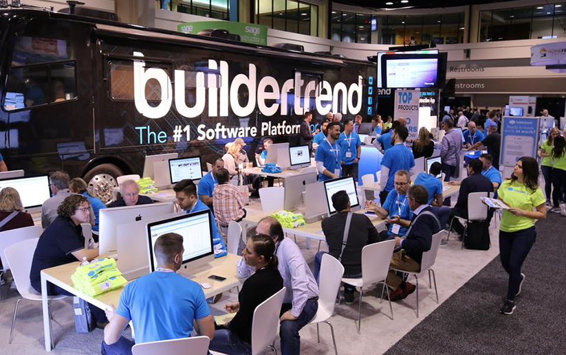 A crowd of people talking and seated at several desks with computers
