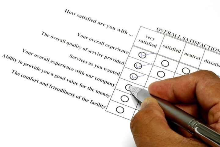 Closeup of a hand making checkmarks on a satisfaction survey