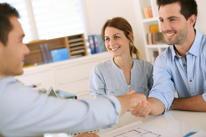 Person shaking hands with a couple across the table
