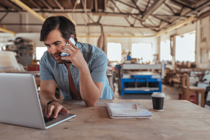 Man looking at laptop while talking on the phone