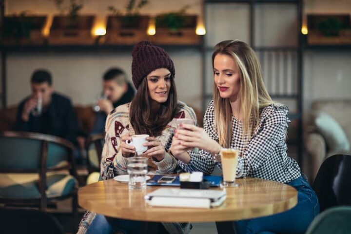 Two women looking at a phone at a cafe