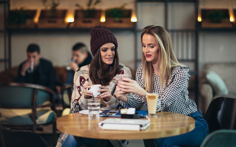 Two women looking at a phone at a cafe