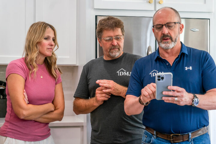General contractor and his team member looking over a construction contract on a home builder app with his female client.