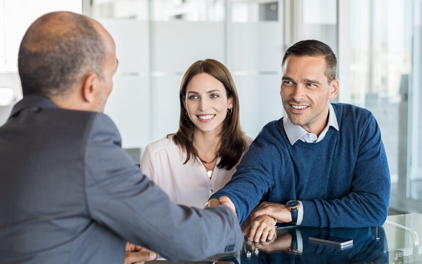 Couple shaking hands with a business man