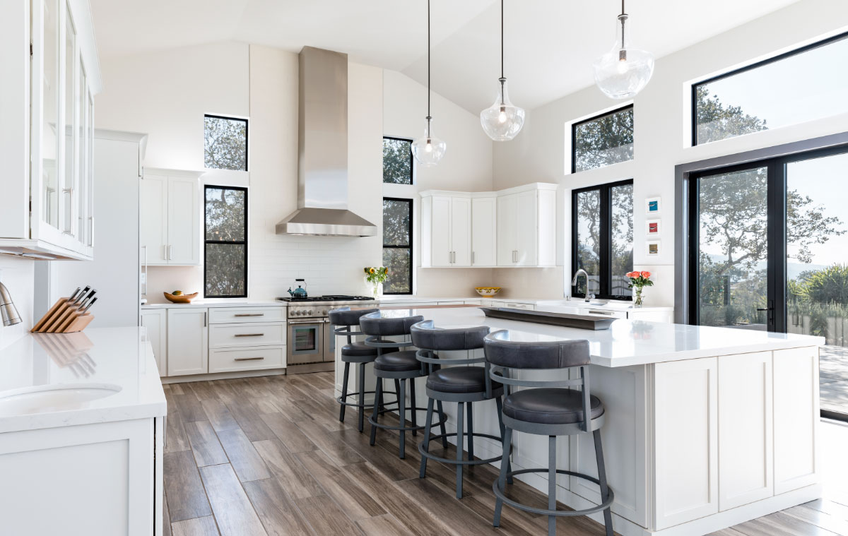 Interior home kitchen with a modern chic theme. Bright counter tops and cabinets juxtaposed to muted wooden flooring.