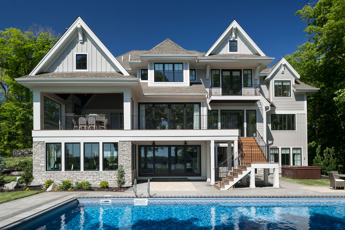 Three story home featuring a glistening pool 