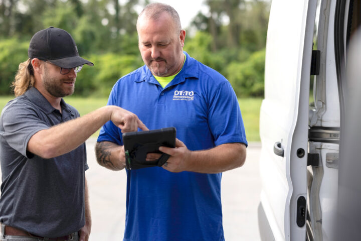 Contractor and crew member review project details in the Buildertrend platform on a tablet