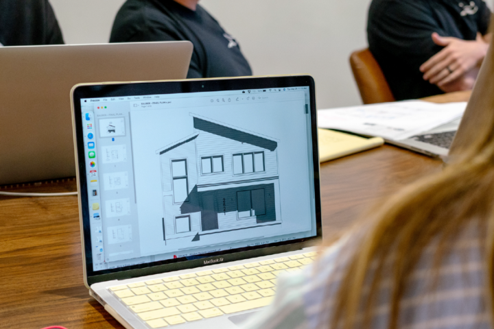 Woman looks at mockup of home exterior on laptop screen
