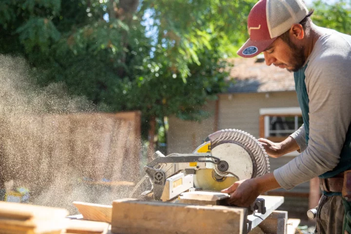 Construction worker sawing a piece of wood.