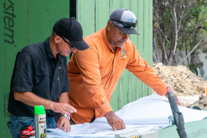 Image of two male construction workers looking over a blueprint together.