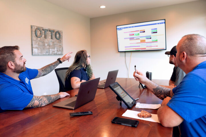 Four people in an office looking at the Buildertrend Schedule