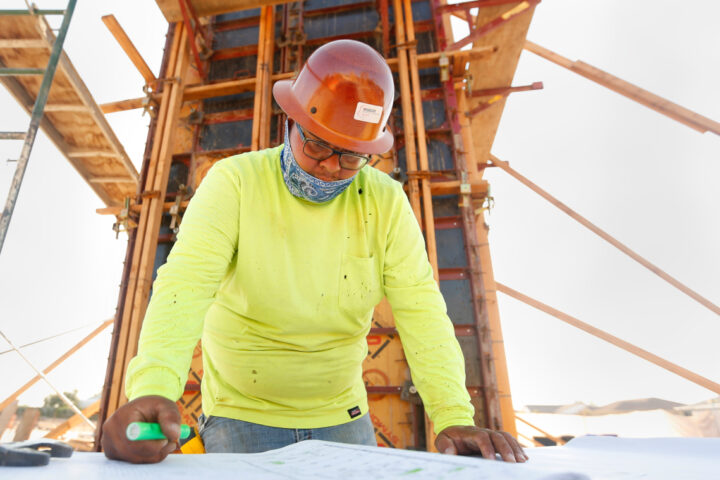 Construction worker in a hard hat looking at blueprints