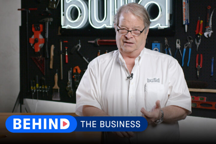 Tim Hill of Risinger Build stands against company backdrop with words "Behind the Business" displayed over the lower third of the screen.