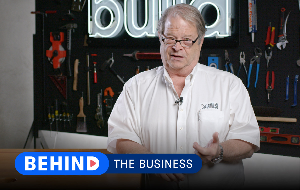 Tim Hill of Risinger Build stands against company backdrop with words "Behind the Business" displayed over the lower third of the screen.