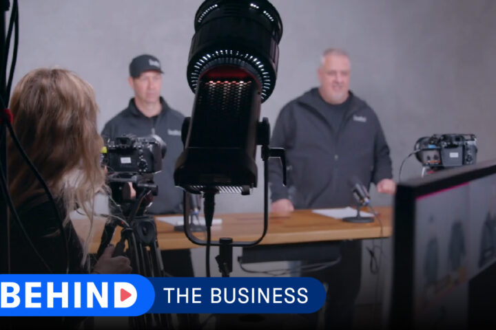 Two builders from Risinger Build behind a light and camera.