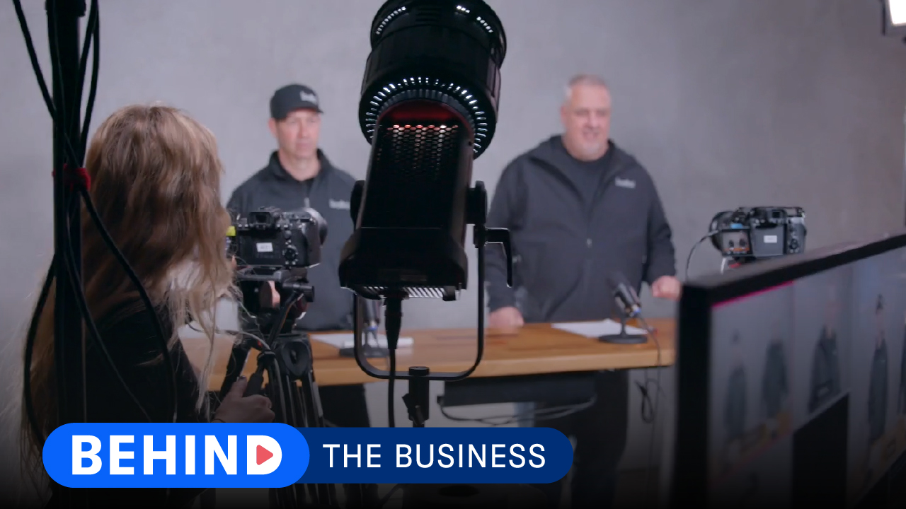 Two builders from Risinger Build behind a light and camera.