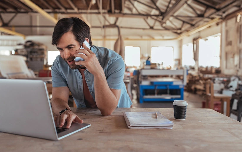 Man working at desk on laptop taking a call