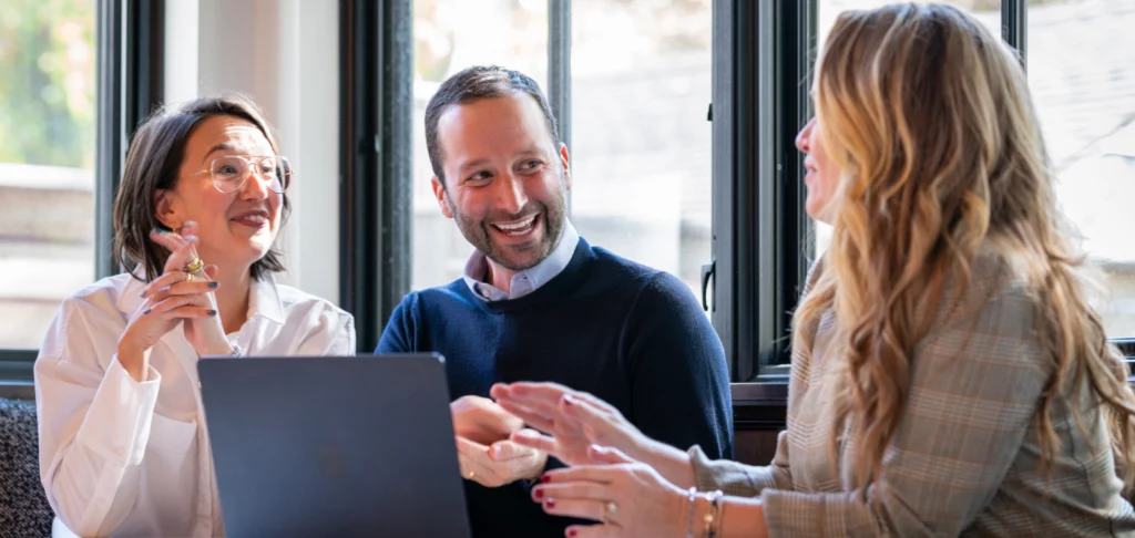Three people having a discussion around a laptop