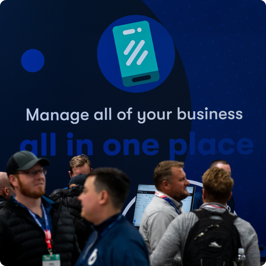 Small crowd of people mingling in front of Buildertrend sign