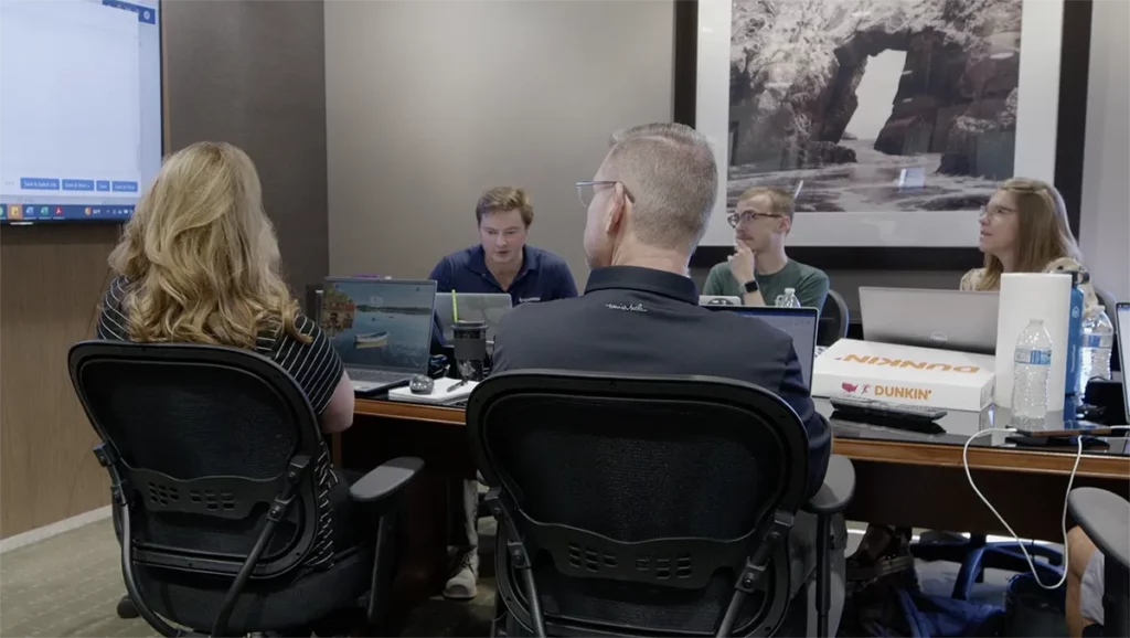 AFT Onsite group of people sitting at table reviewing screens