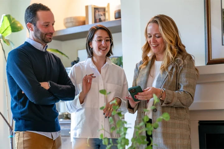 Two women and one man looking at an ipad and chatting