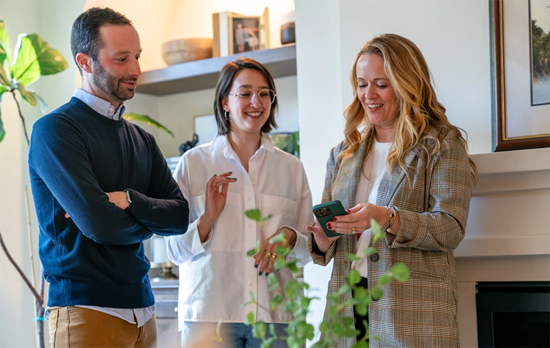 Two women and one man looking at an ipad and chatting