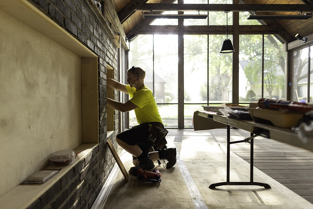man tiling a wall inside of a house