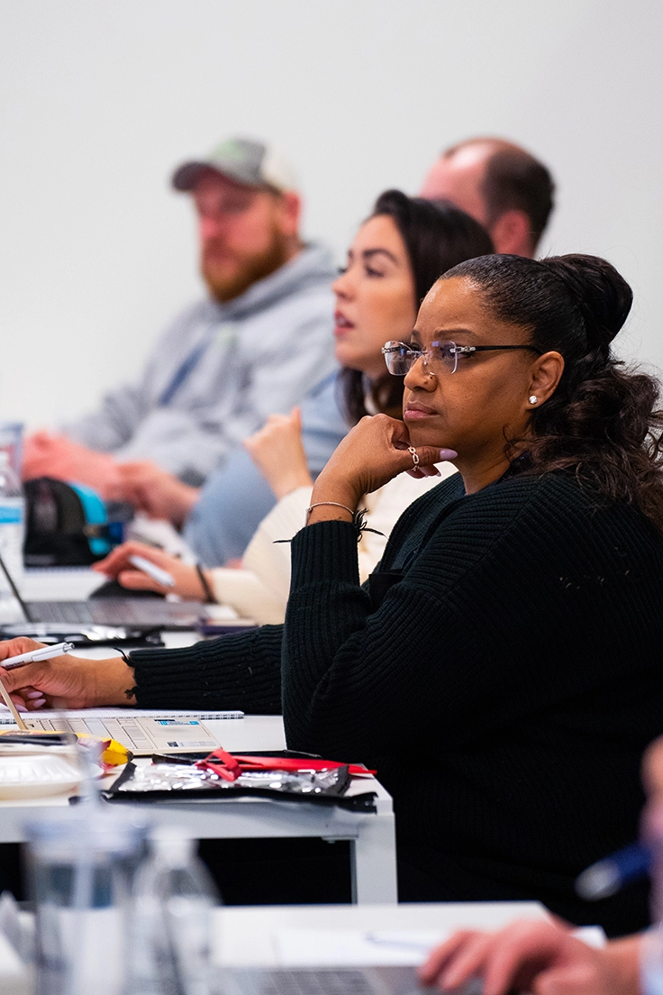 men and women sitting at a desk in a classroom