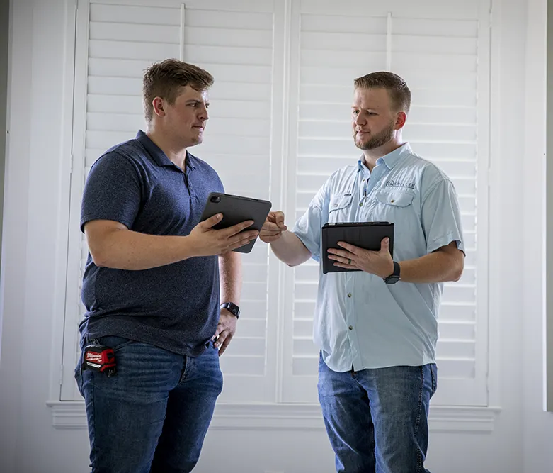 two men standing up and reviewing tablets