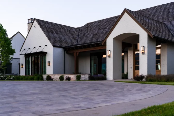 A white custom home with a black roof and a concrete driveway