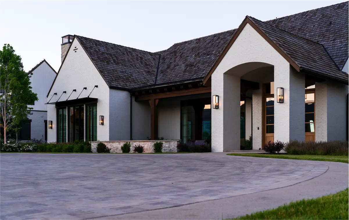 A white custom home with a black roof and a concrete driveway