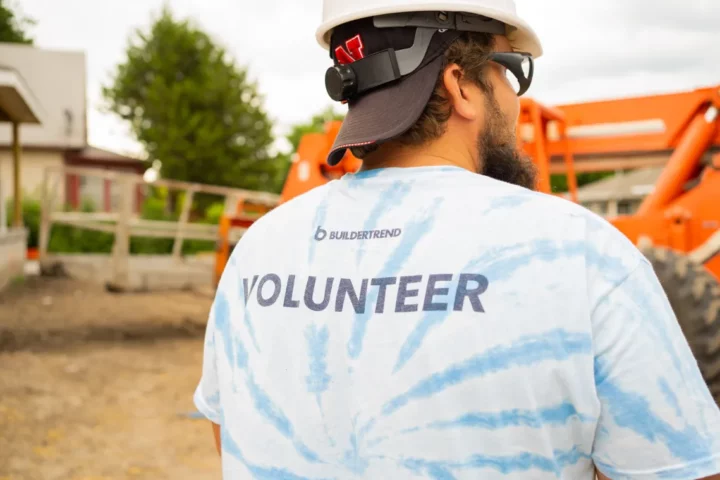A man in a hard hat with his back turned in a tshirt that says Buildertrend volunteer