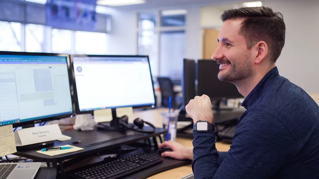 Man sitting at desk with two computer monitors