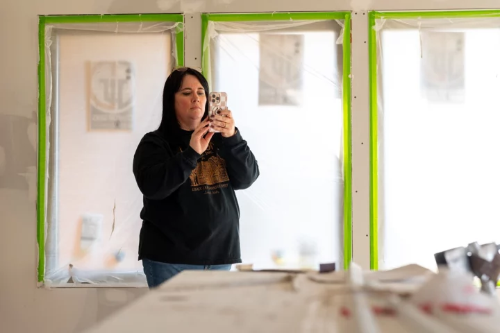 A woman standing in a construction site holding up her phone