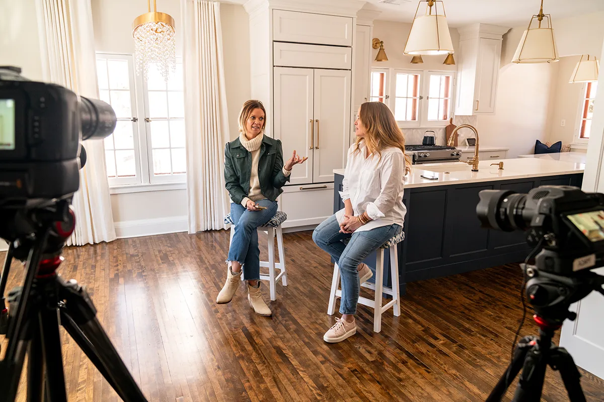Two women sitting on stools having a conversation