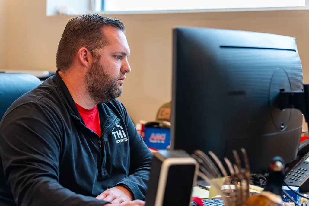 man sitting at desk and computer monitor