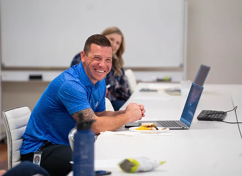 zoomed in photo of man smiling in front of laptop
