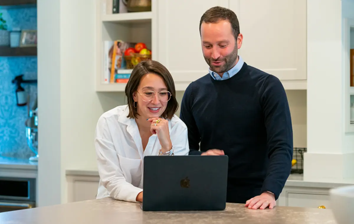Two builders looking at a laptop screen together