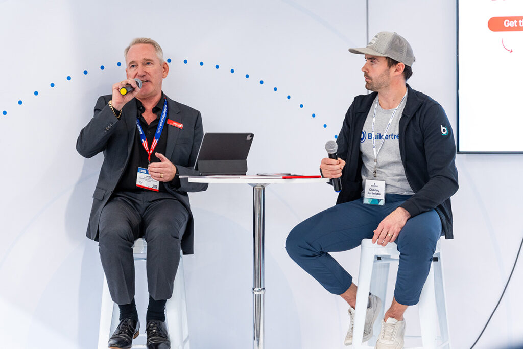 two men sitting at a table, speaking