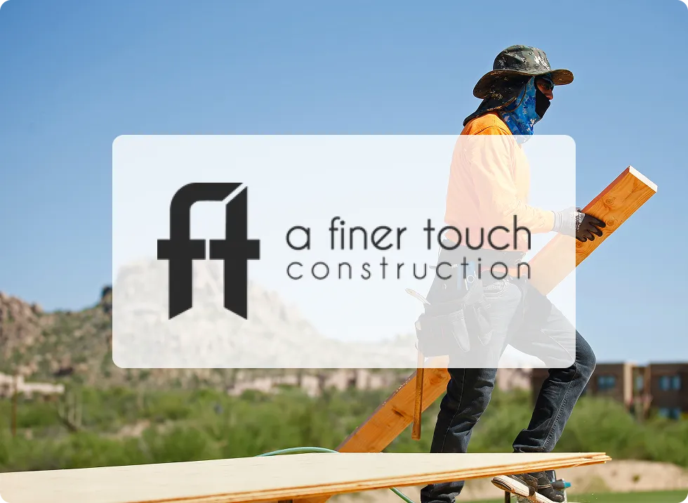 A Finer Touch Construction logo with man carrying lumber in the background