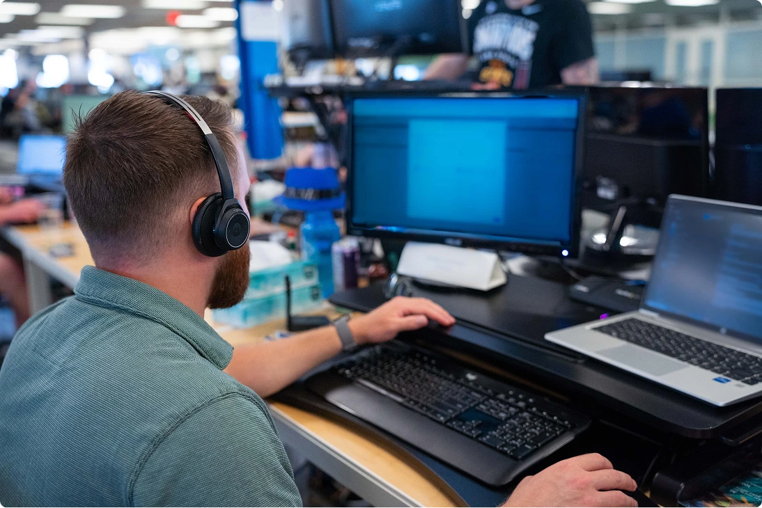 Team member with headphones looking at multiple screens while working in Buildertrend headquarters.