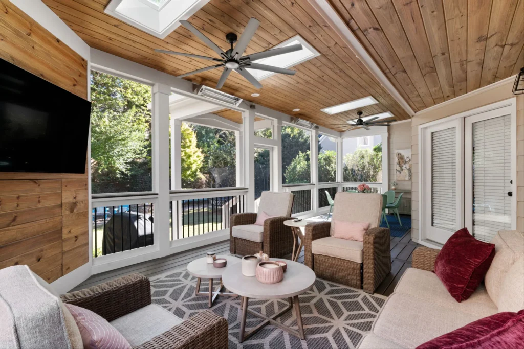 Covered outdoor patio with wicker seating, ceiling fans, wood ceiling, and dining area